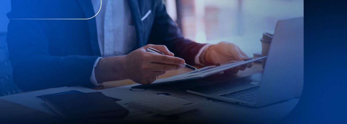 Homem escrevendo em tablet com notebook ao fundo