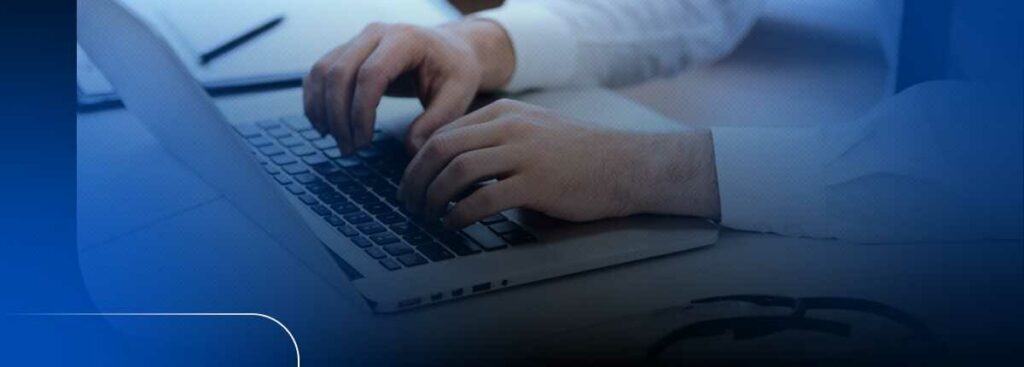 Mãos digitando em laptop sobre mesa de trabalho