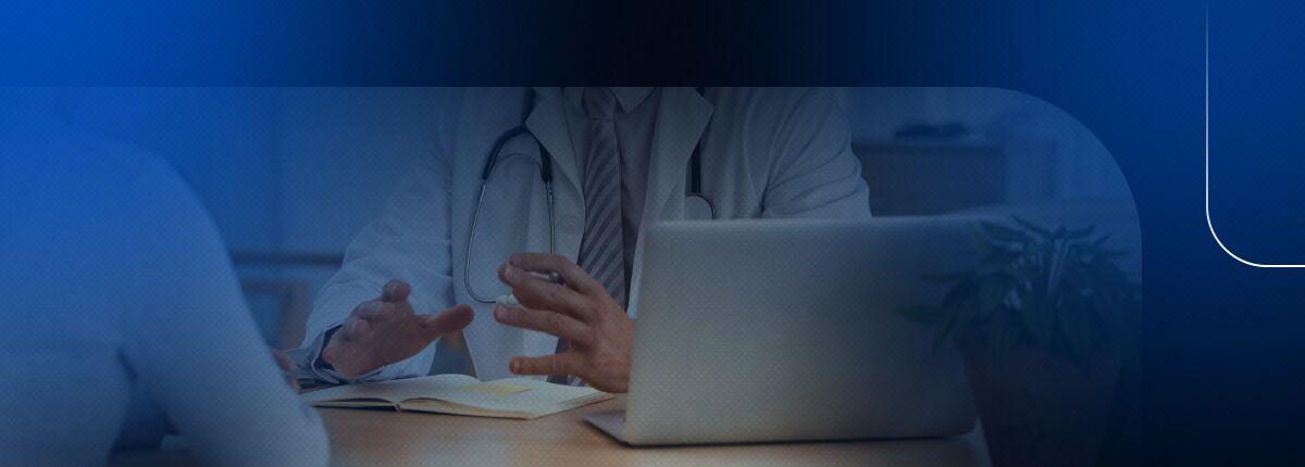 Médico em consulta com paciente, laptop sobre a mesa