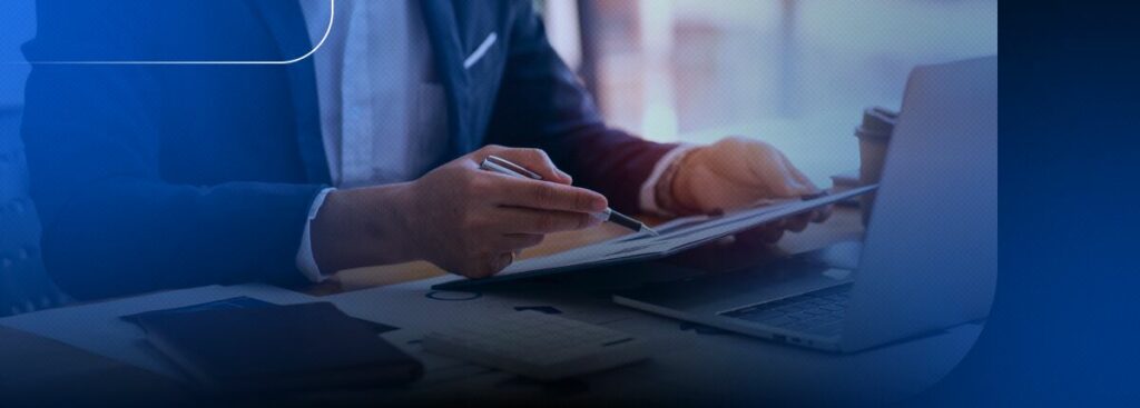 Homem escrevendo em tablet com notebook ao fundo