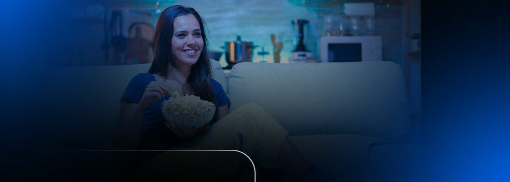 Mulher assistindo TV com pipoca no sofá