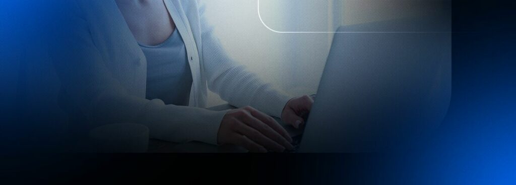 Pessoa digitando no laptop com um fundo azul.